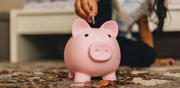 Child puts coins in piggy bank